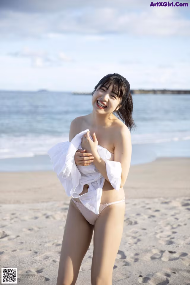 A woman in a white bikini standing on a beach.