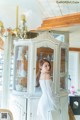 A woman standing in front of a white china cabinet.