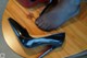 A pair of black high heels sitting on top of a wooden table.