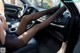 A woman sitting in the driver's seat of a car with her legs up.