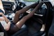 A woman sitting in the driver's seat of a car with her legs up.