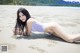 A woman in a white bikini laying on the beach.