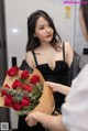 A woman in a black dress holding a bunch of red roses.