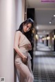 A woman leaning against a wall in a hallway.