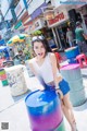 A woman sitting on top of a colorful barrel.