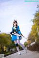 A woman in a blue and white outfit holding a sword.