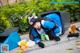 A woman in a blue and white outfit laying on the ground next to a trash can.