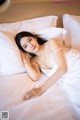 A woman laying on a bed in a white dress.