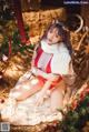 A woman in a red and white lingerie sitting next to a Christmas tree.