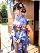 A woman in a blue kimono standing in front of a building.