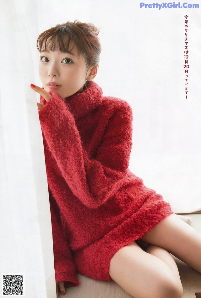 A woman in a red sweater sitting on a window sill.