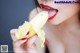 A woman is eating a banana with her tongue out.