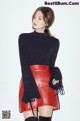 a woman in a black sweater and red leather skirt