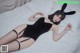 A woman laying on a bed wearing a black bodysuit and bunny ears.