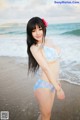 A woman in a blue bikini standing on a beach.