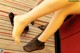 A woman in black stockings and high heels sitting on a red chair.