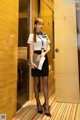 A woman in a white shirt and black skirt standing in an elevator.