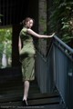 A woman in a green dress standing on a set of stairs.