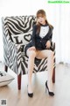 A woman sitting on a chair in a zebra print chair.