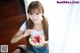 A young woman eating a slice of watermelon with a spoon.