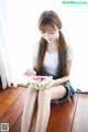 A woman sitting on the floor eating a slice of watermelon.