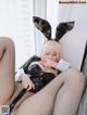 A woman in a bunny costume is sitting on a bed.