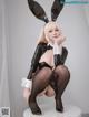 A woman in a bunny costume sitting on a white pedestal.