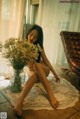 A woman sitting on the floor next to a vase of flowers.