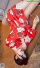 A woman in a red kimono laying on a wooden table.