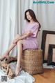 A woman sitting on top of a wicker basket on a wooden floor.