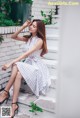 A woman sitting on the steps of a white brick building.