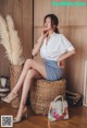 A woman sitting on top of a wicker basket next to a handbag.