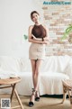 A woman standing in front of a white couch.