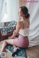 A woman sitting on the floor in a pink skirt.