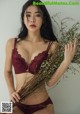 A woman in a red bra and panties holding a bunch of flowers.