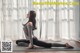 A woman is sitting on a yoga mat in front of a window.