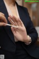 A woman in a business suit holding a pen.