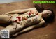 A naked woman laying on a wooden table covered in sushi.