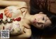 A naked woman laying on a wooden floor covered in sushi.