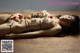 A naked woman laying on a wooden table covered in sushi.