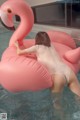 A woman in a white bathing suit is floating on an inflatable flamingo.