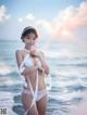 A woman in a white bikini standing on the beach.