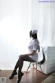 A woman sitting on a chair in front of a washing machine.