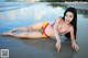 A woman in a colorful bikini laying on the beach.